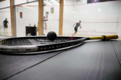 Squash racket with ball close up, laying on table, preparing for game. cour.. Stock Photos
