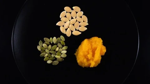 Squash soup rotates on black plate with pepitas over dark background. 4K Video stock 74060489