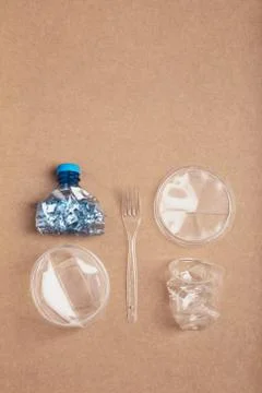 Squashed plastic bottle, box, cup and fork over cardboard background Stock Photos
