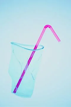Squashed plastic cup and drink straw over blue background Stock Photos
