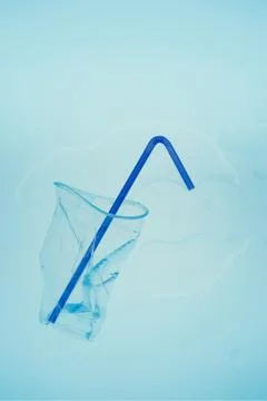 Squashed plastic cup and drink straw over blue background Stock Photos