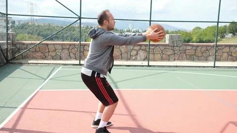 Squat basketball, young man doing squats with basketball, in court Stock Footage 164072116