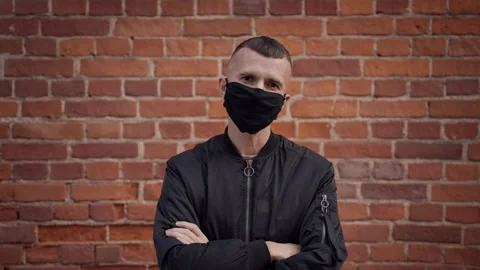Squat in black jacket removes protective mask, spits, looks at camera. Stock Footage 163768027