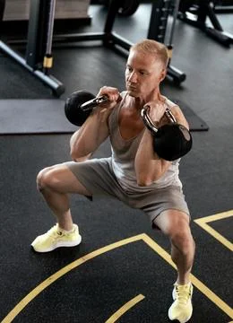 Squats with kettlebells exercise. Middle aged athlete doing functional workou Stock Photos