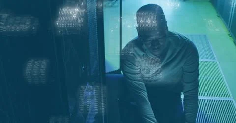 Squatting technician plugging cables at server rack in data center, binary code Stockfoto's