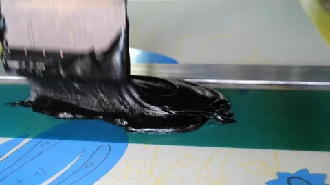 Squeegee draws black dye through a mesh screen onto fabric revealing a floral Video stock 339123510