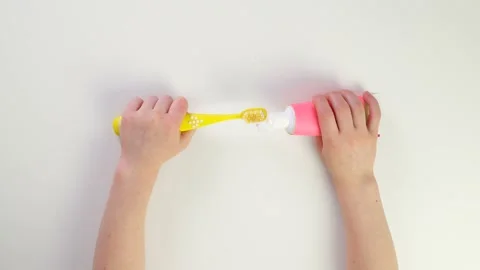 Squeeze baby toothpaste onto the brush. Top view of children's caucasian hands Stock Footage 170934678