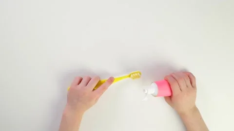 Squeeze baby toothpaste onto the brush. Top view of children's caucasian hands Stock Footage 170934809