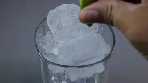 Squeeze a drop of lemon juice into a glass of ice for a refreshing drink. wil Stock Footage 190817505
