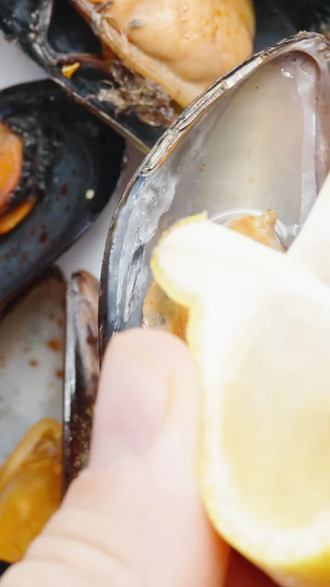 Squeeze the lemon juice onto the mussels while they rotate. Close-up.Vertical, S Stock Footage 258295384