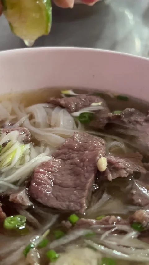 Squeeze lime juice into soup hands picking up small bowl of chinese noodle soup Stock Footage 316076180