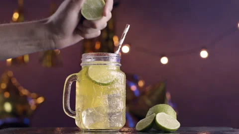 Squeeze lime in mojito cocktail with party background at night Stock Footage 135560684