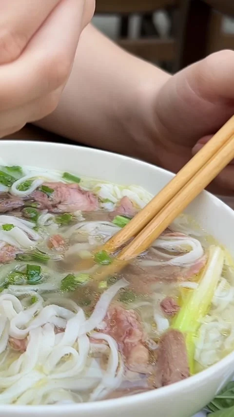 Squeeze into lime soup hand squeezes lime over a bowl of pho in a bustling Stock Footage 309258169