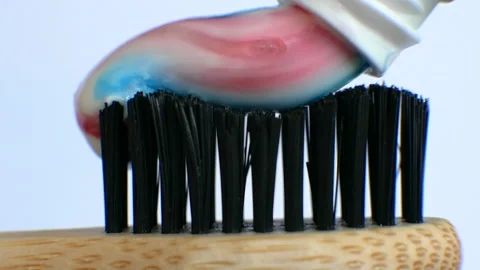 Squeeze multi-colored toothpaste on a wooden toothbrush Stock Footage 212166758