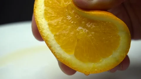 Squeeze orange macro on the white plate. Video stock 85744632