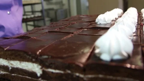Squeeze the white cream on a dark sponge cake production Stock Footage 80587740