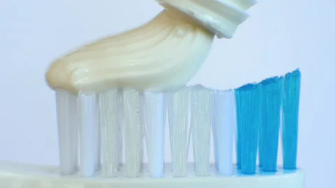 Squeeze white toothpaste onto a plastic toothbrush on a white background. Stock Footage 212166914