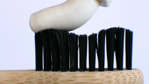 Squeeze white toothpaste onto a wooden toothbrush on a white background. Stock Footage 212167360