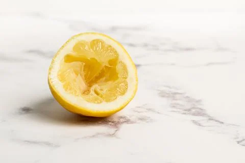 Squeezed half lemon on marble kitchen countertop in a close up view Stock Photos