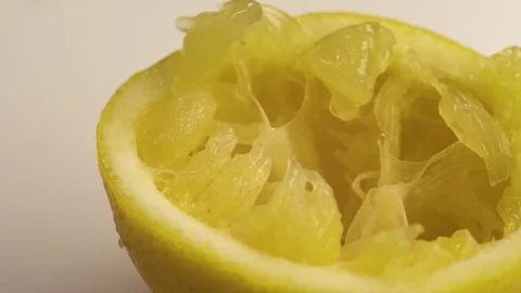 Squeezed lemon lies on a white table. The white table is spinning, or the camera Stock Footage 126612995