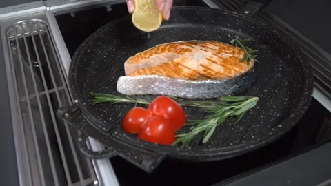 Squeezed lemon into a pan with salmon. Slow motion Video stock 101734872