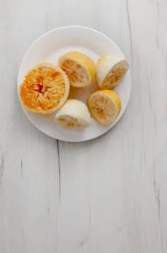 Squeezed lemons close-up on a white plate on a background of gray wooden tabl Stock Photos