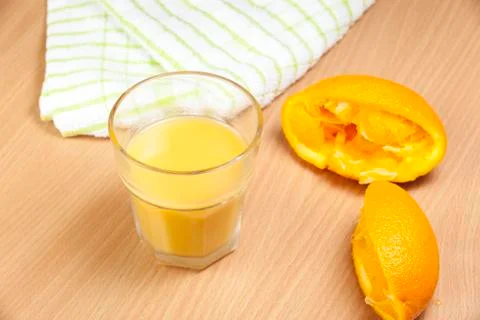 Squeezed orange halves next to a filled glass Stock Photos