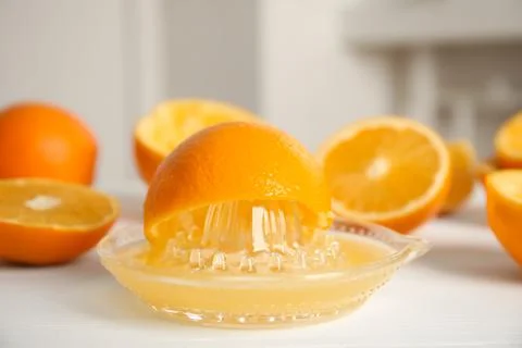 Squeezer and cut fresh oranges on white table, closeup Stock Photos