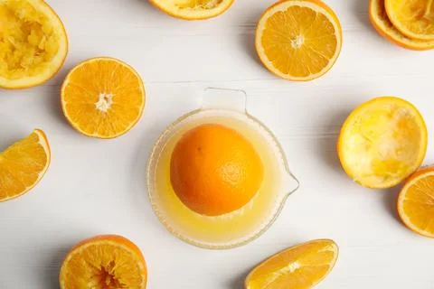 Squeezer and cut fresh oranges on white wooden table, flat lay Stock Photos