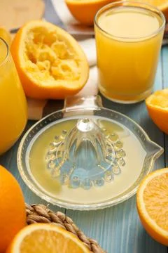 Squeezer, fresh oranges and juice on blue wooden table Stock Photos
