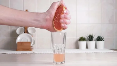 Squeezes juice from grapefruit into a glass. Freshly squeezed fresh. Stock Footage 142190872