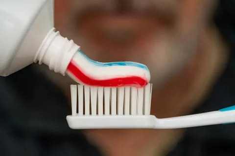 Squeezing colored toothpaste onto a toothbrush. Stock Photos
