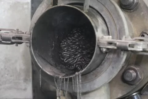 Squeezing dark, polypropylene out of the pressing chamber. Фото