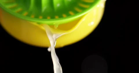 Squeezing fresh juice with a lemon squeezer in a kitchen setting for drinks and Stock Footage 325087722