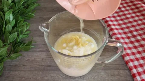 Squeezing fresh lemon juice into yogurt sauce with pink citrus juicer - 4K Stock Footage 345956647