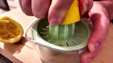 Squeezing fresh lemon with manual citrus juicer Stock Footage 345080935