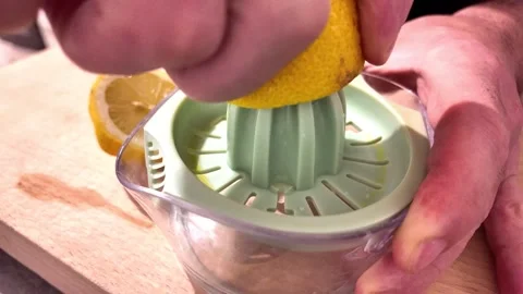 Squeezing fresh lemon with manual citrus juicer Stock Footage 345080939