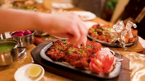 Squeezing Fresh Lemon Over Sizzling Chicken Tikka Tandoori Platter Stock Footage 345024579