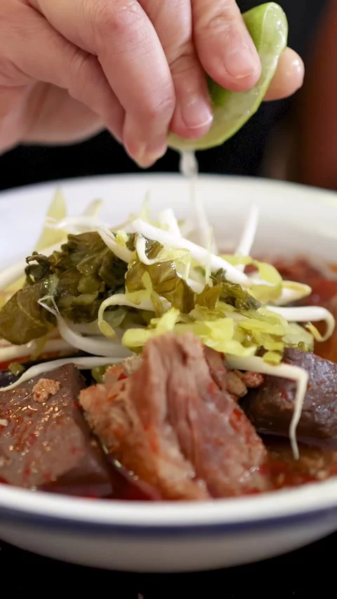 Squeezing Fresh Lime Over Northern Thai Curry Noodle Soup Stock Footage 314413467