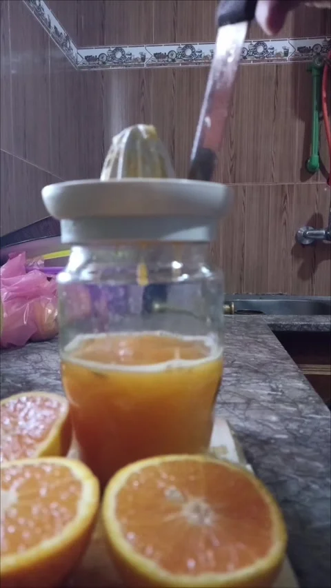 Squeezing Fresh Orange Juice into Glass Jar in Kitchen Video stock 336871978