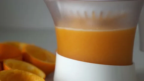 Squeezing fresh oranges using electric juicer in the kitchen making juice. Stock Footage 158198086