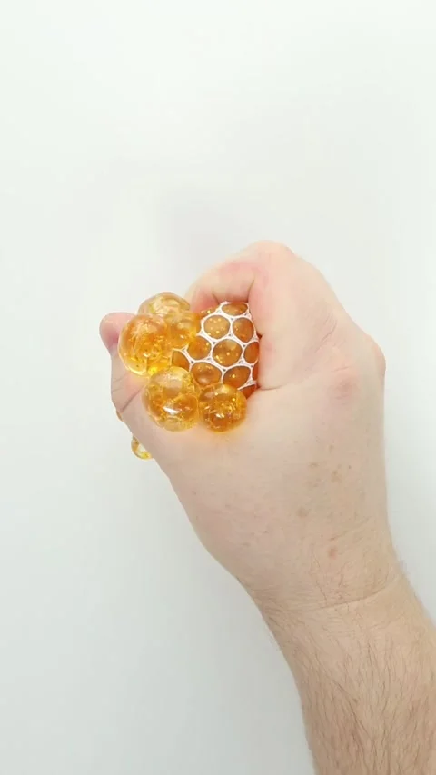 Squeezing golden gel bead stress ball for relaxing ASMR squish Stock Footage 336264878