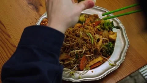 Squeezing kaffir lime over a plate of thai stir-fried rice noodles. Pad thai, a Stock Footage 307706754