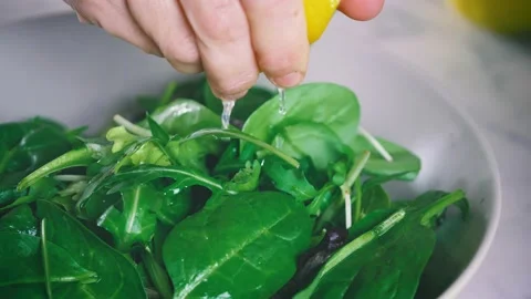 Squeezing lemon on fresh salad. Chef preparing a dish full of green leaves  Stock Footage 146922442