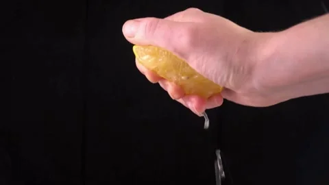 Squeezing a lemon half on black background. Citrus fruit source of vitamins and Stock-Footage 336588498