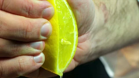 Squeezing a lemon half on black background. Citrus fruit source of vitamins and Stock-Footage 336588744