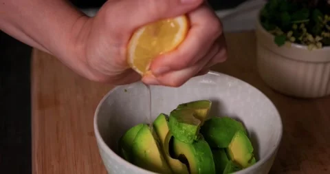 Squeezing lemon juice on fresh sliced avocado in a bowl. Stock Footage 152590309