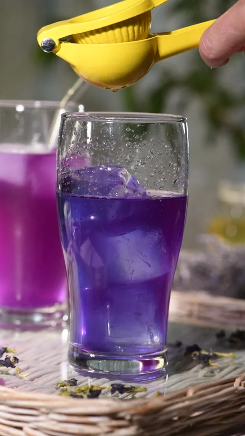 Squeezing Lemon Juice into Iced Butterfly Pea Tea — Part 3 Stock Footage 345887845