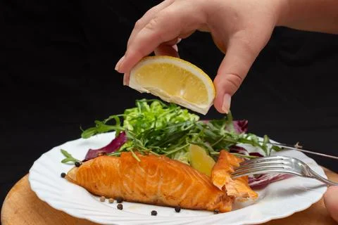 Squeezing lemon juice over cooked salmon steak Stock Photos