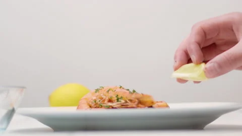 Squeezing lemon juice on top of freshly made fried shrimps/prawns in 4K. Stock Footage 138287381